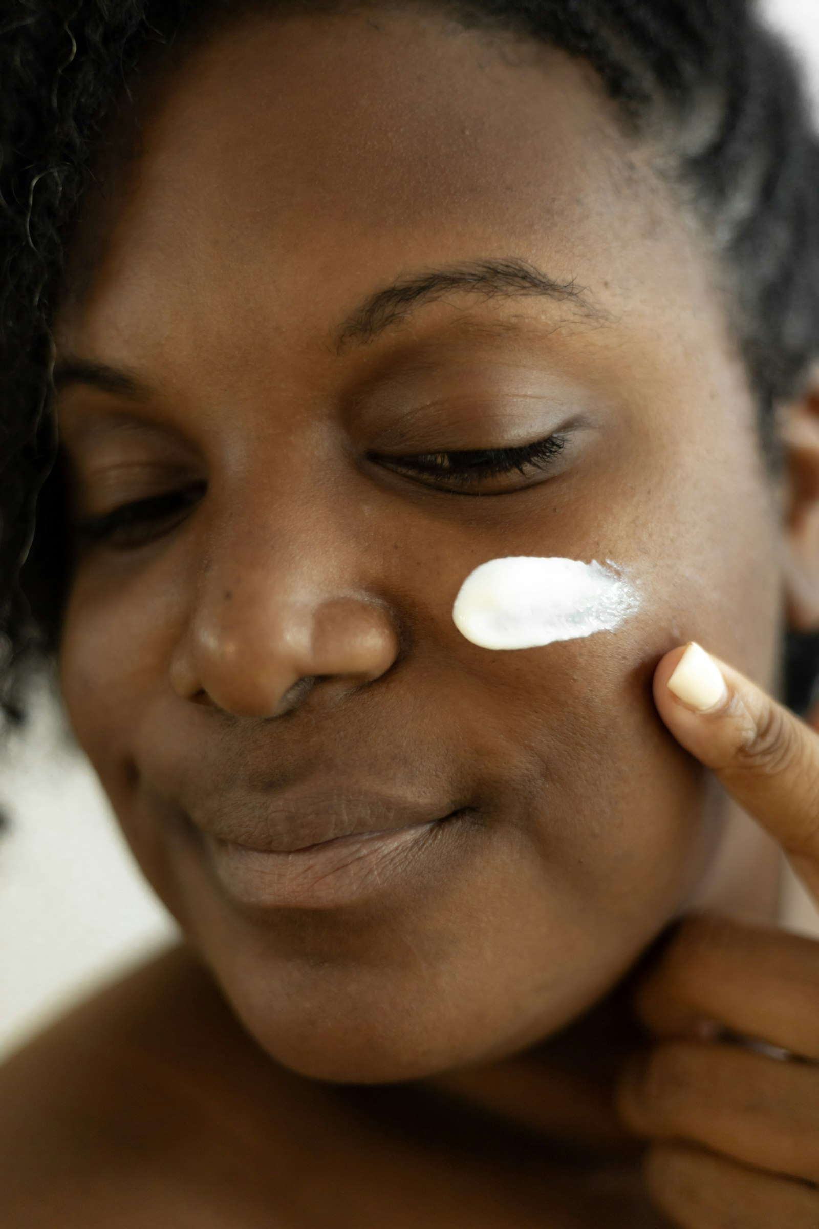 Woman applying a dab of moisturizer to her cheek